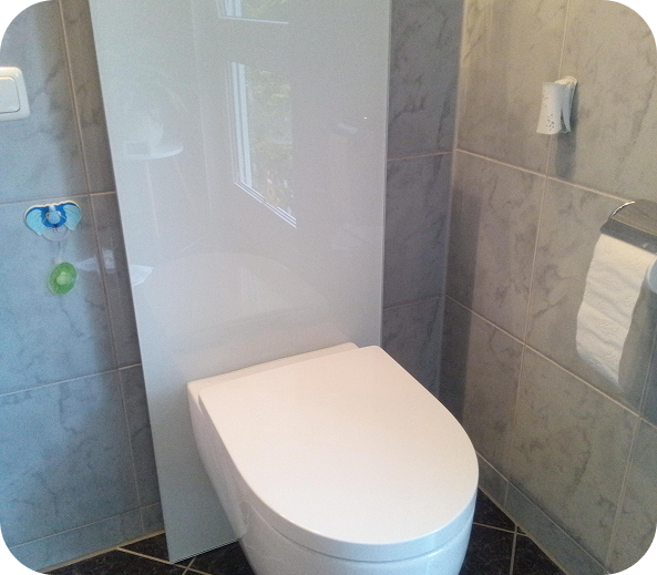 Moderner weißer Wand-WC-Sitz in einem Badezimmer mit grauen Fliesen und zwei Schnullern an der Wand.