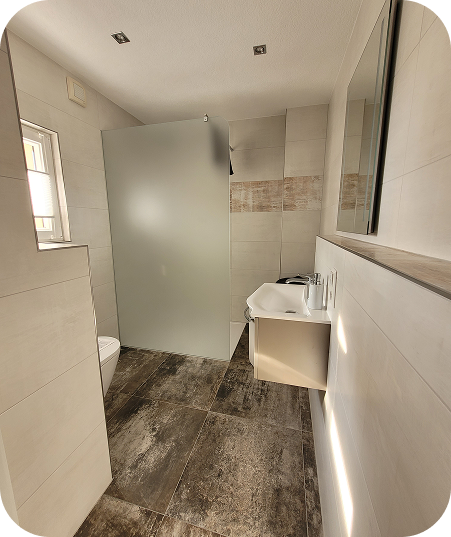 Modernes Badezimmer mit hellen Wandfliesen, dunklem Boden, einer Toilette, einem wandhängenden Waschbecken und einer halbtransparenten Duschwand.