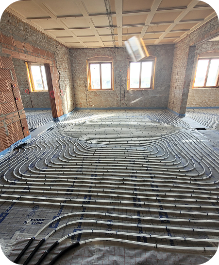 Rohbau eines Raums mit großen Fenstern und einer installierten Fußbodenheizung unter dem Bodenbelag.