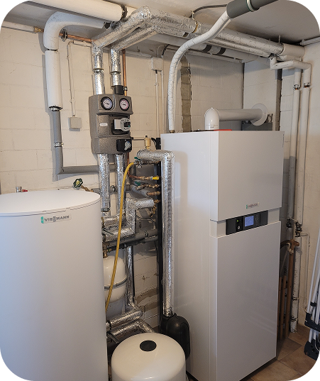 Heizungsanlage mit isolierten Rohren und Steuerungen in einem Kellerraum.