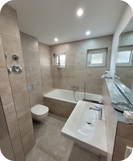 Modernes Badezimmer mit Badewanne, Wandtoilette und weißem Waschbecken mit großem Spiegel.