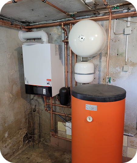 Heizungsanlage mit einem weißen Wandgerät, einem großen runden Ausdehnungsgefäß und einem orangefarbenen Warmwasserspeicher in einem Kellerraum.