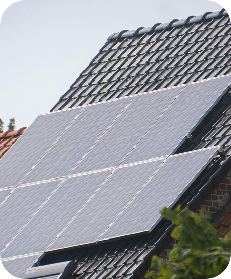 Solarmodule auf einem schwarzen Ziegeldach eines Hauses bei klarem Himmel.