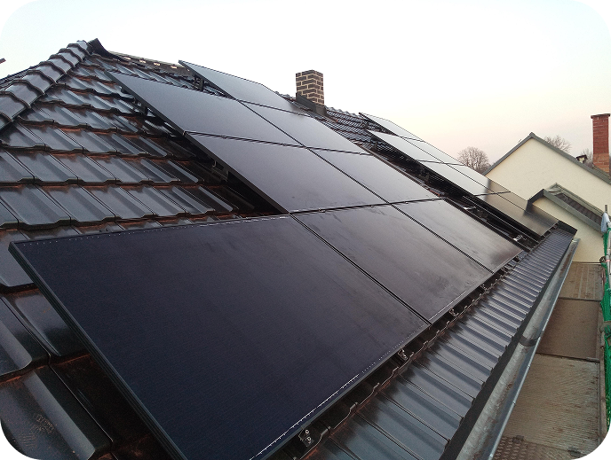 Dach mit installierten schwarzen Solarpaneelen auf einem Haus.