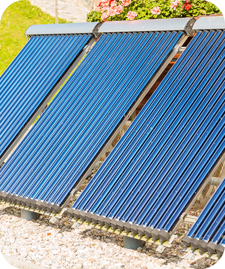 Reihen von blauen Vakuumröhren-Solarthermie-Kollektoren im Freien auf Kiesboden mit Blumen im Hintergrund.