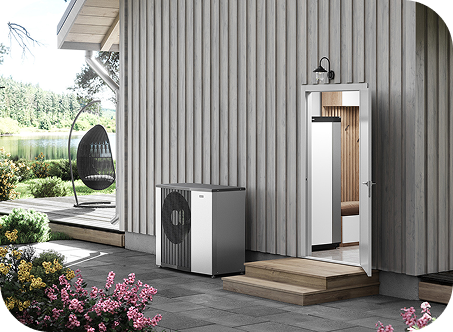 Außenansicht eines modernen Hauses mit einer hellen Holzfassade, einer Wärmepumpe auf der Veranda und einem Schaukelstuhl im Garten.