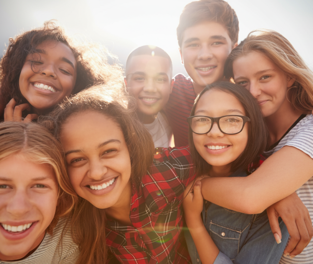 A group of smiling teenagers posing for a photo outdoors.