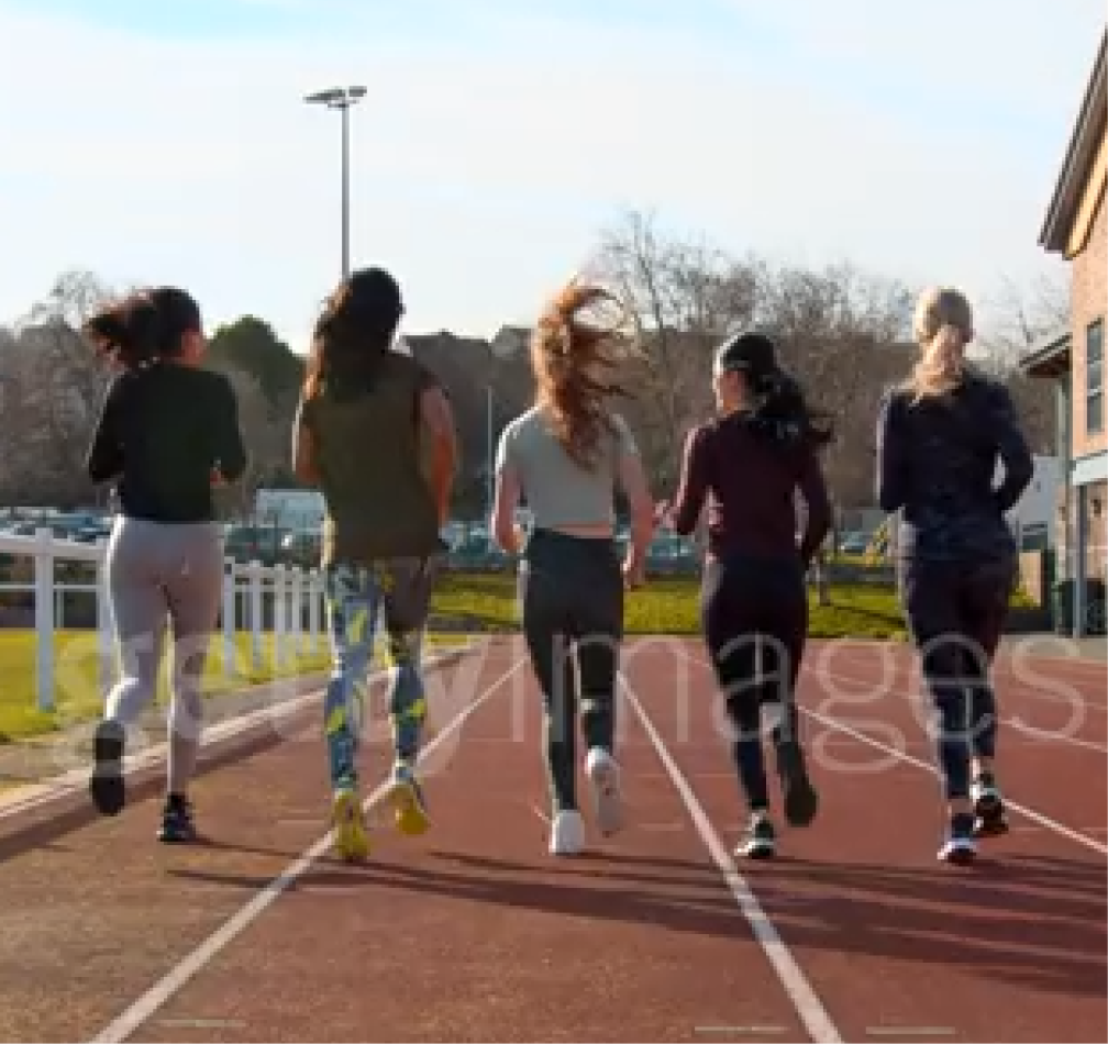 A group of teenagers running on a track together outdoors.
