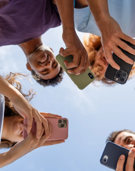 ow-angle shot of three people holding smartphones against a blue sky.