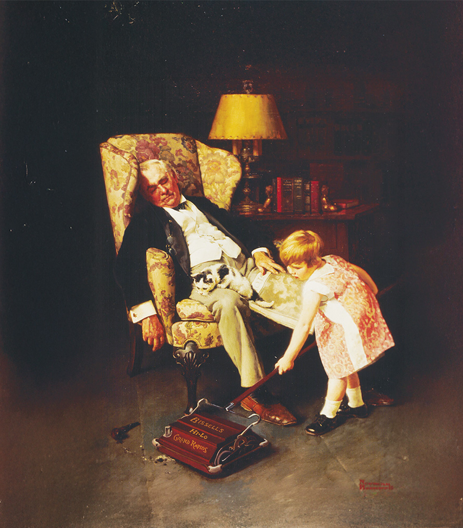 A man asleep in a floral armchair with a cat on his lap as a girl pets a vacuum cleaner on the floor.
