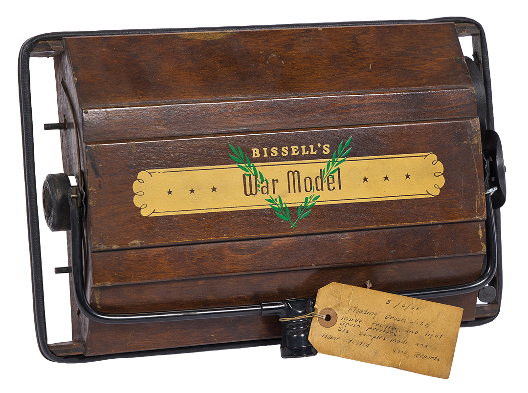Bissell's War Model wooden box vacuum cleaner with metal frame and attached handwritten tag.