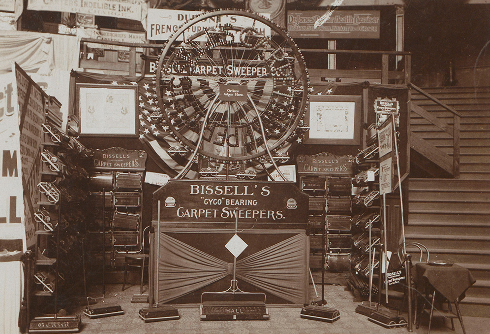 Vintage display of Bissell's Gyco bearing carpet sweepers with a large Ferris wheel-style product showcase.