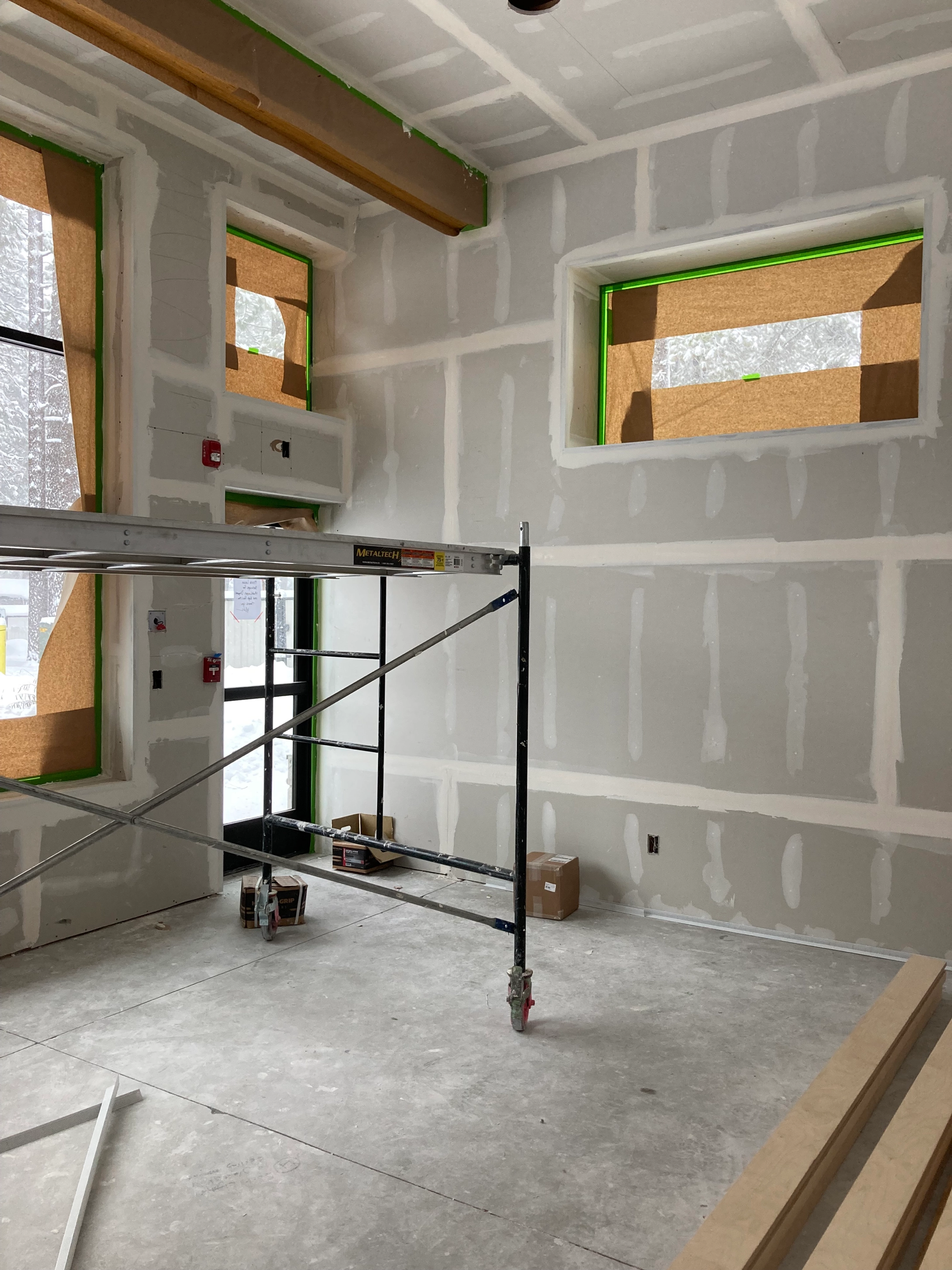 Professional drywall installation in progress with scaffold in foreground