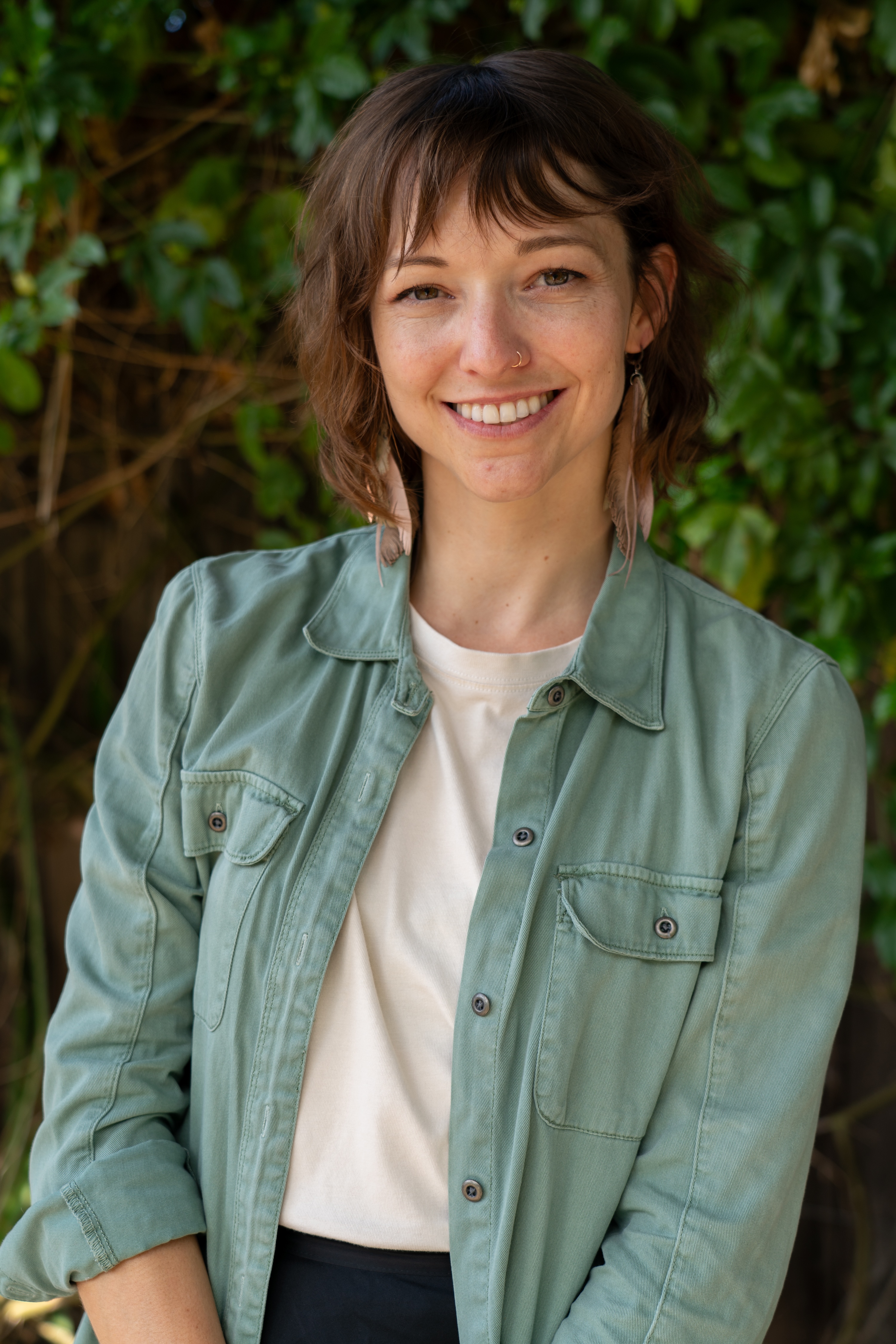 Professional headshot of Kelly Lovejoy, a therapist specializing in grief and trauma, in a natural setting with soft, cinematic lighting.