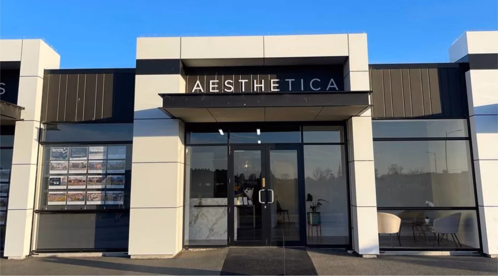 Modern storefront with glass double doors and large windows, featuring the sign AESTHETICA above the entrance.