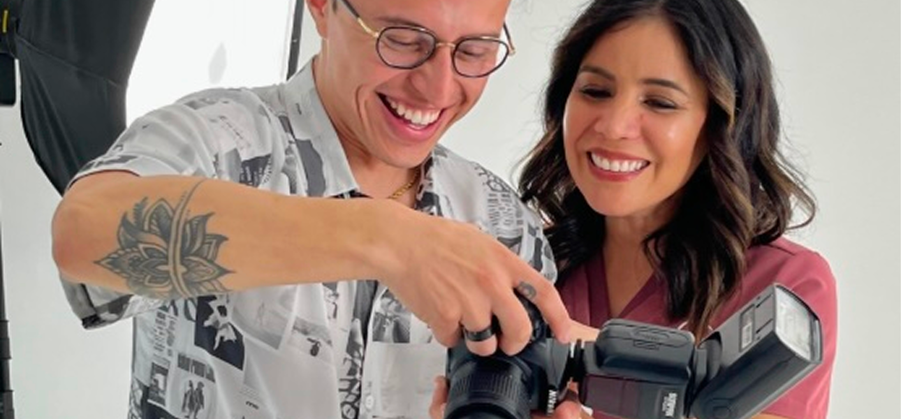 Dos personas sonrientes revisan una cámara fotográfica con flash en un estudio.