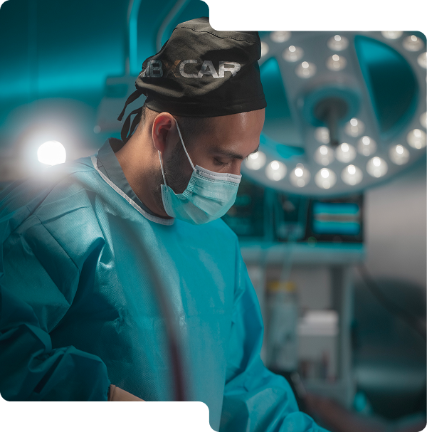 Cirujano masculino con gorro y mascarilla quirúrgica concentrado durante una operación en quirófano.