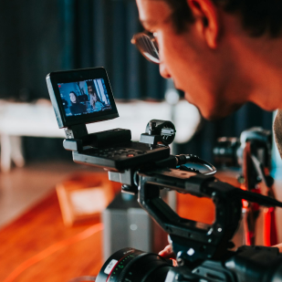 Persona usando una cámara profesional con pantalla desplegable que muestra una escena grabada.