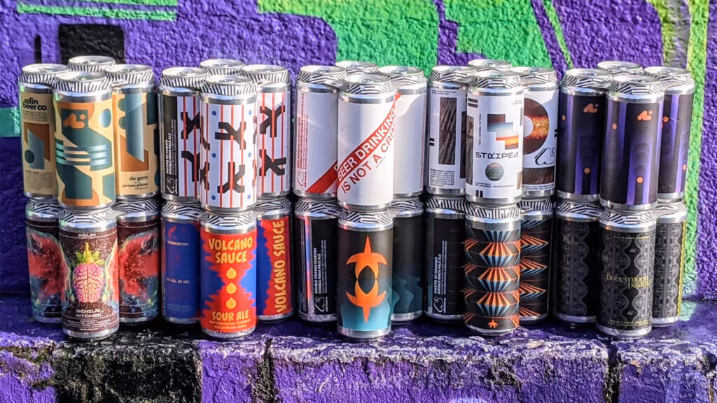 A collection of various Aslin Brewery custom designed been cans stacked in a group. 