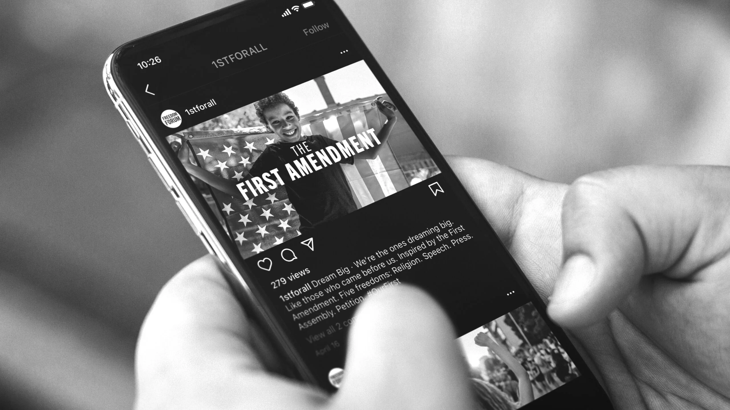 A smartphone displaying a Freedom Forum First Amendment campaign post featuring a child with an American flag.