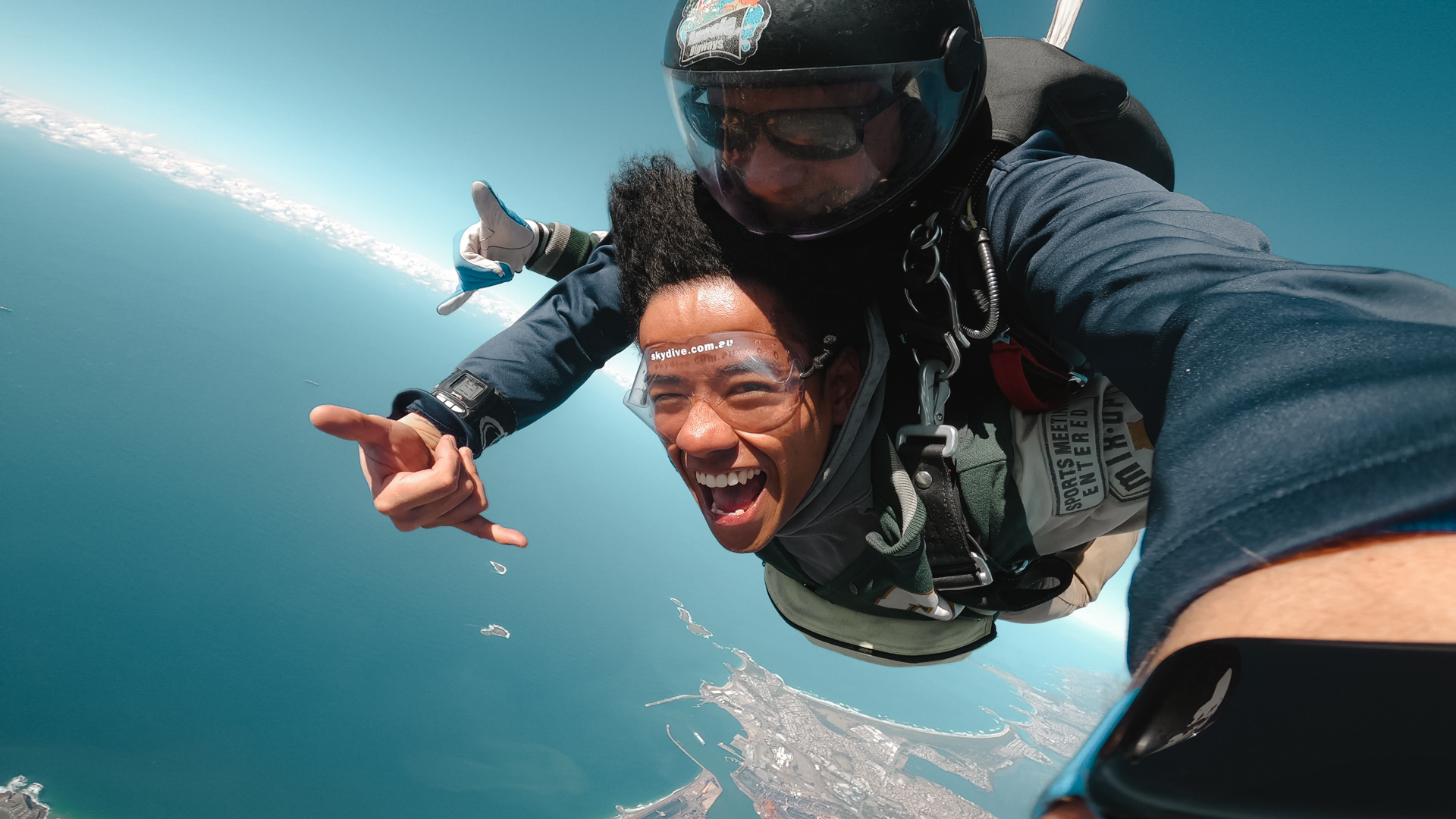 Two people skydiving above the coastline