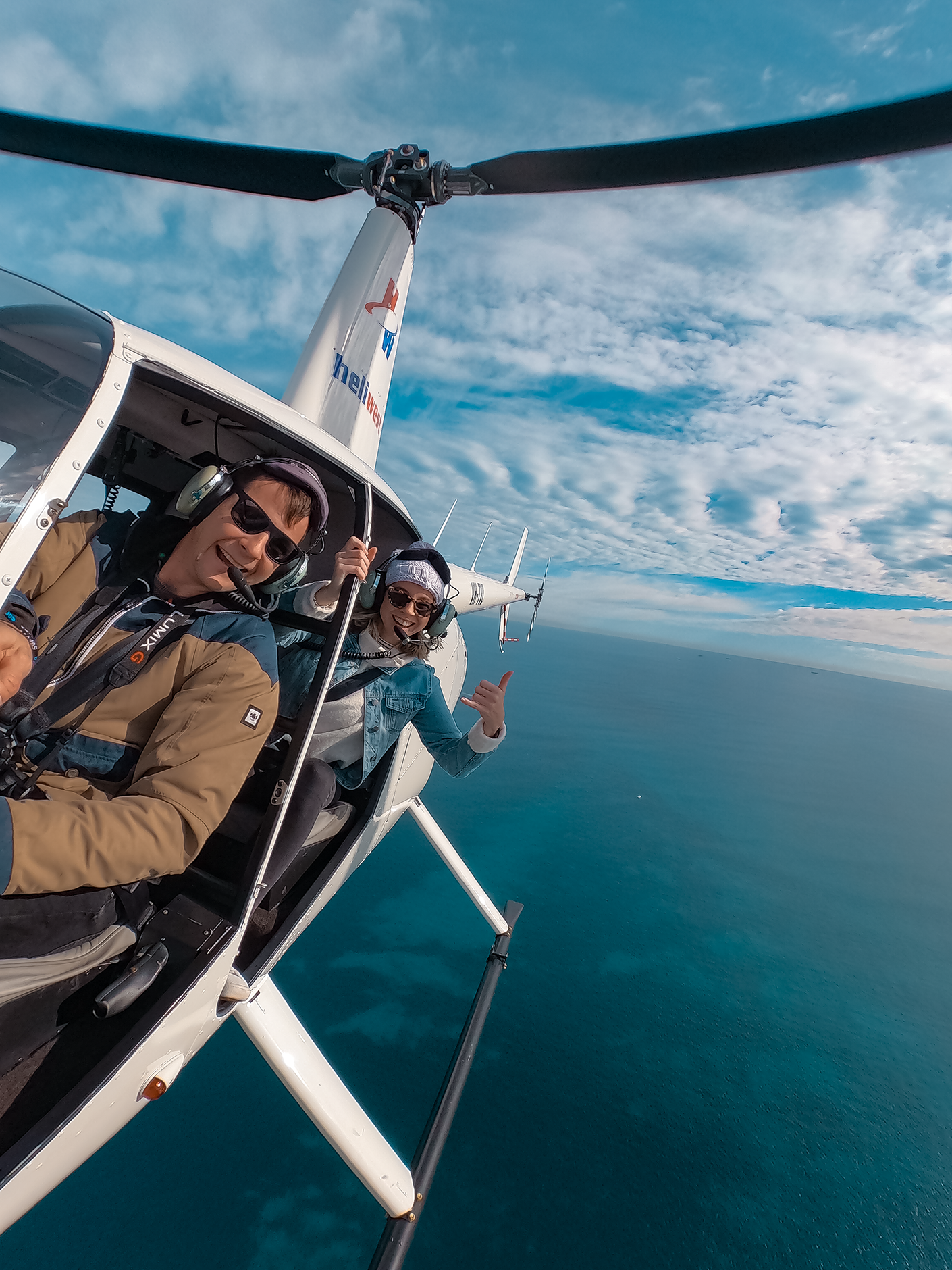 helicopter pilot and passenger taking a selfie whilst flying above the ocean