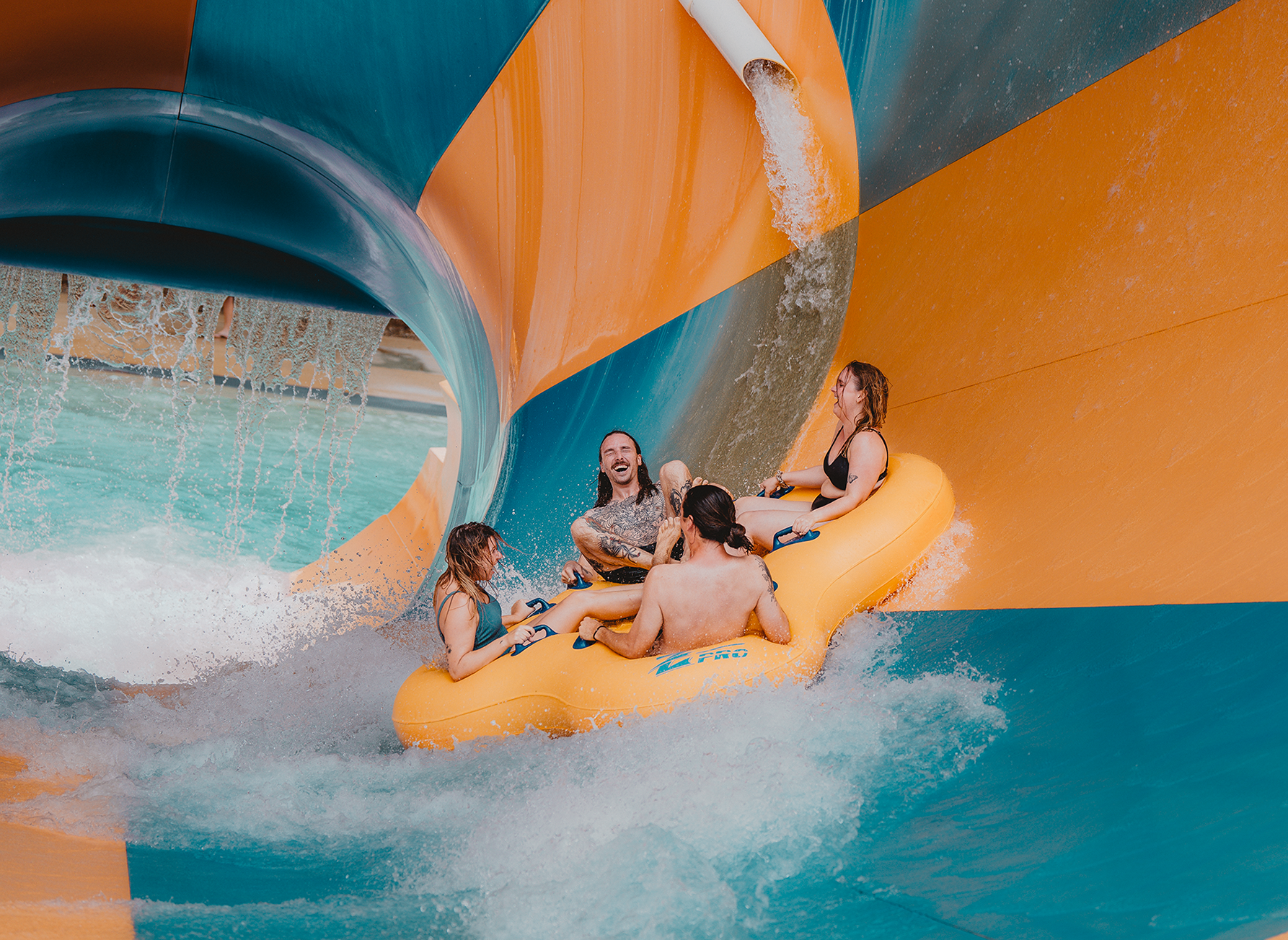 4 people riding a rubber ring on a waterpark slide