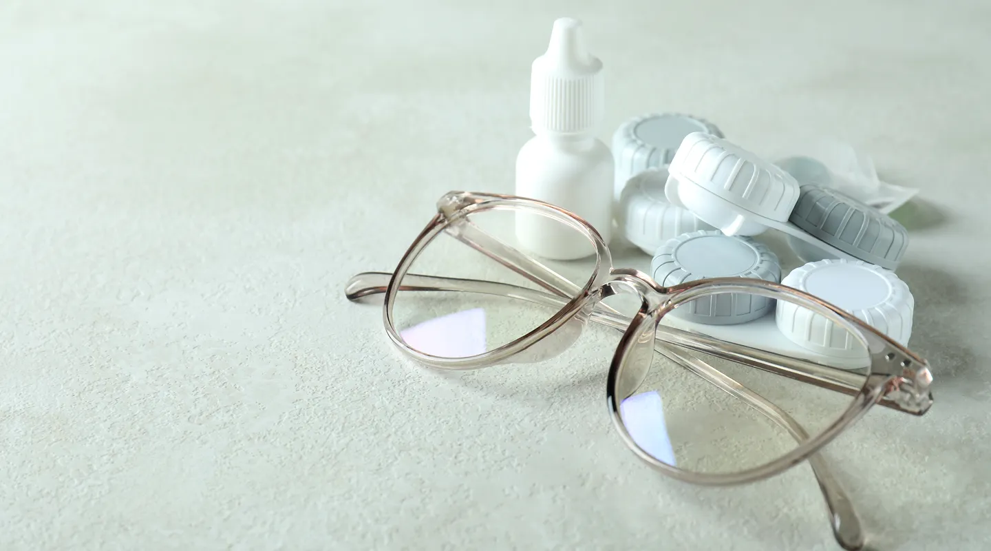 Contact lens care essentials with solution, cases and prescription glasses showing vision correction options