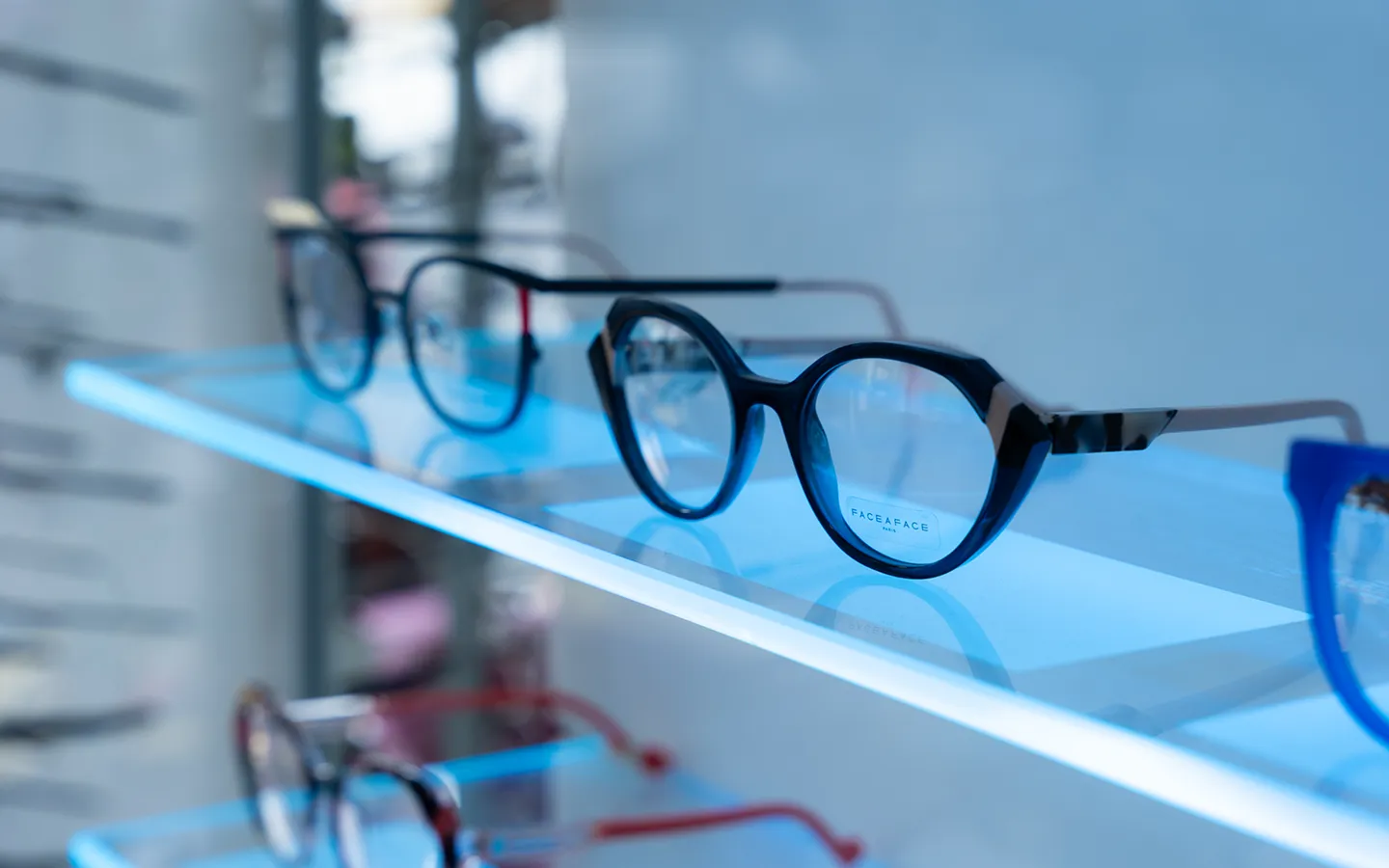 Face a Face designer eyeglasses displayed on illuminated blue shelf in optical practice showroom