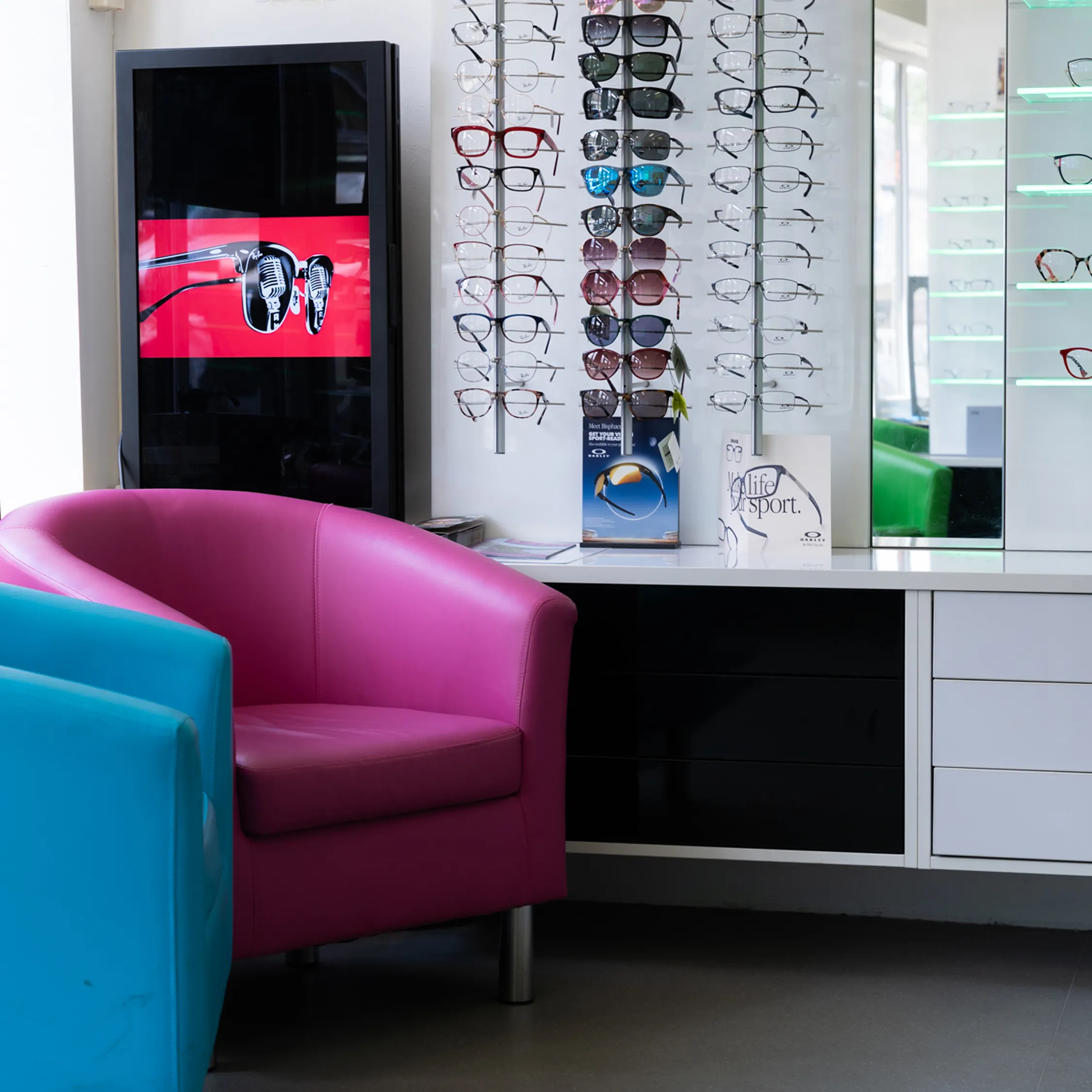 Modern opticians waiting area with colorful seating and designer eyewear display wall