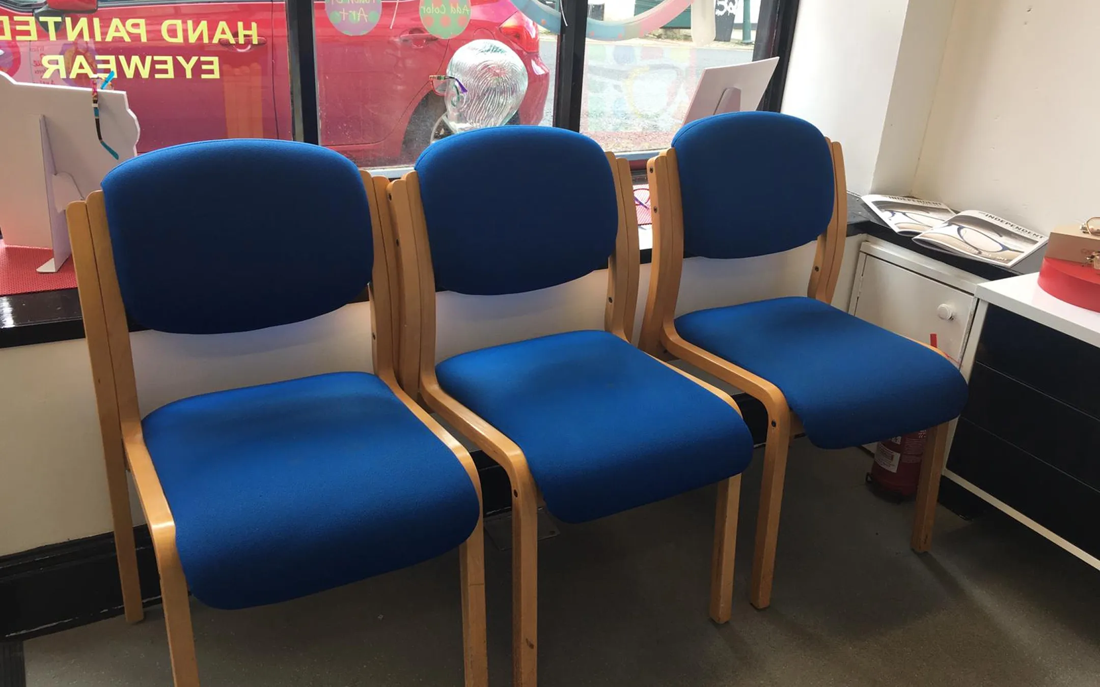 Comfortable opticians waiting room with blue seating and patient information area