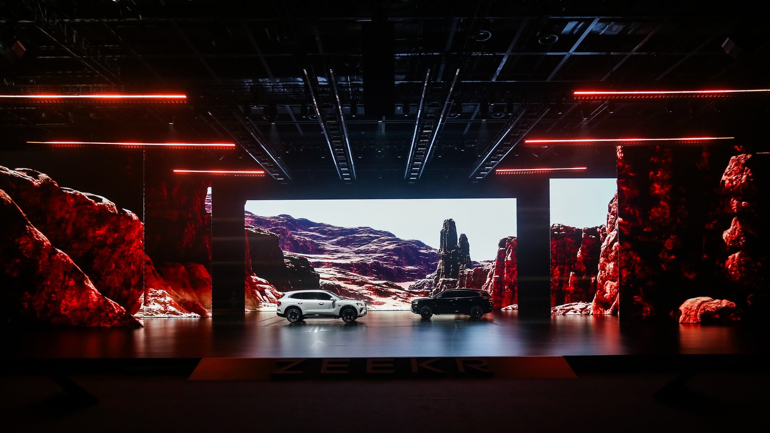 ZEEKR 8X launch event with immersive red LED stage environment, cinematic landscape backdrop and dual vehicle reveal