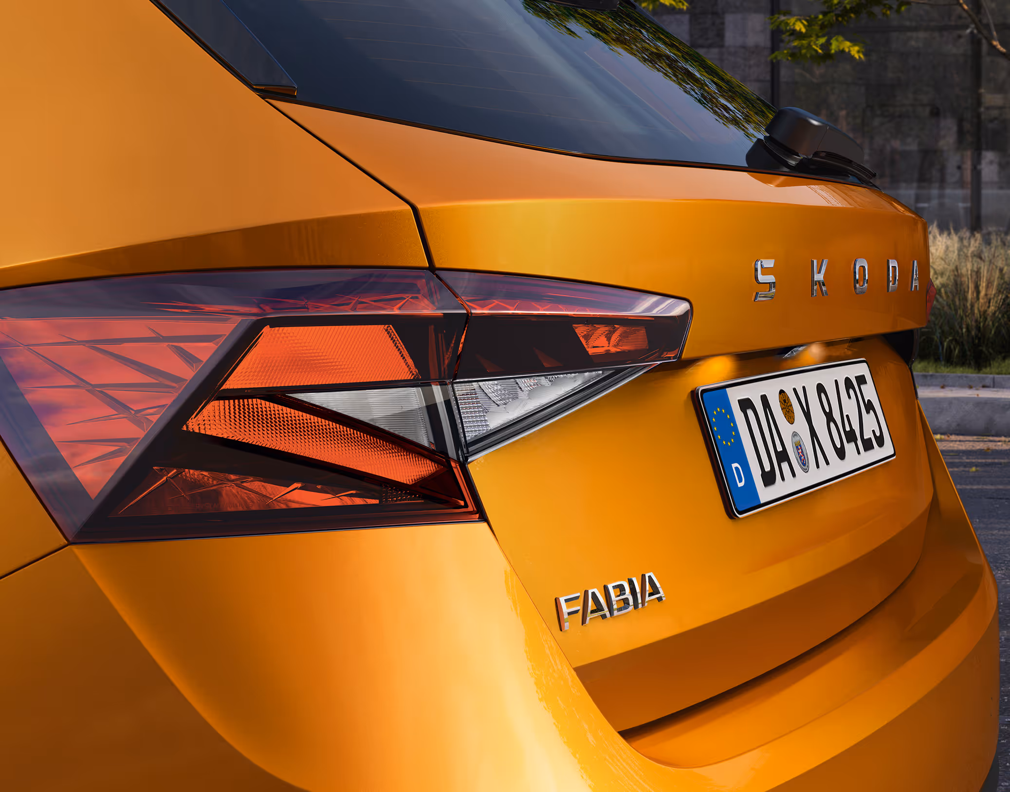 Detailaufnahme der Heckpartie eines Škoda Fabia Balance in der Lackierung Phoenix-Orange Metallic. Zu sehen sind die markant geformte Rückleuchte sowie die verchromten Schriftzüge „ŠKODA“ und „FABIA“ auf der Heckklappe.