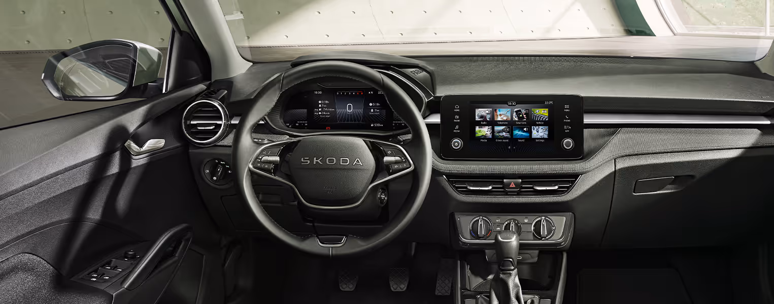 Blick in das Interieur des Škoda Fabia Balance mit Fokus auf das Cockpit und das Armaturenbrett. Zu sehen sind das 2-Speichen-Multifunktionslenkrad vor dem digitalen Kombiinstrument sowie das zentral platzierte Infotainment-Display. Drei grüne Plus-Symbole heben interaktive Bereiche hervor.