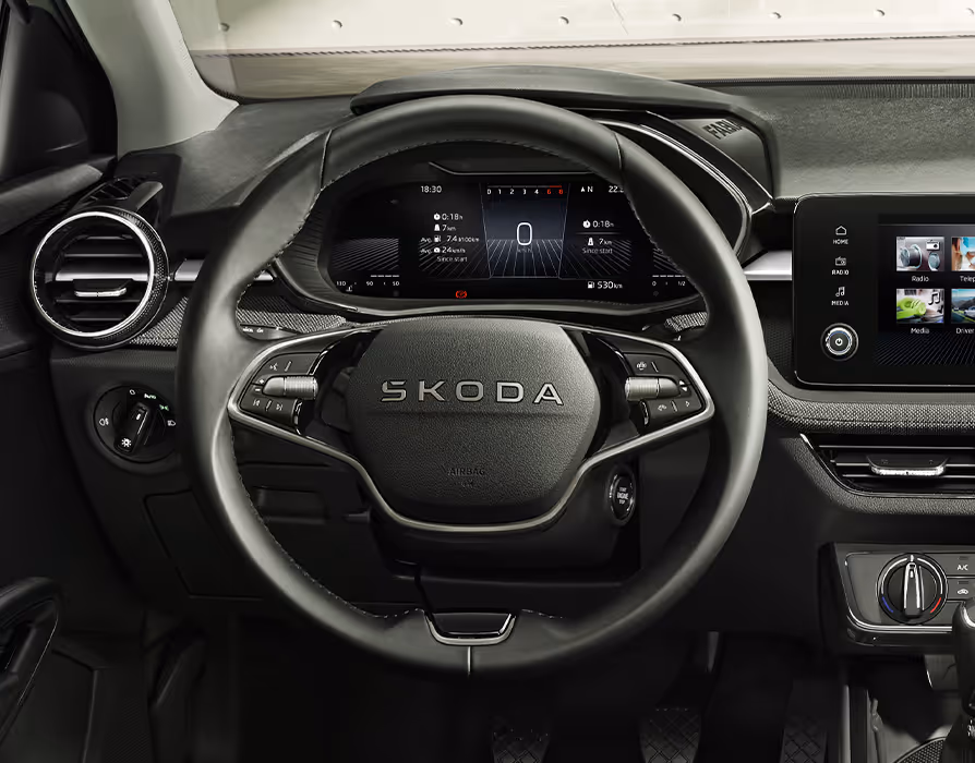 nnenraumaufnahme des Škoda Fabia Balance aus der Fahrerperspektive. Zentral zu sehen ist das 2-Speichen-Multifunktionslenkrad mit Škoda Schriftzug. Dahinter befindet sich das Digital Cockpit, flankiert von einer runden Lüftungsdüse links und dem Infotainment-Display auf der rechten Seite.