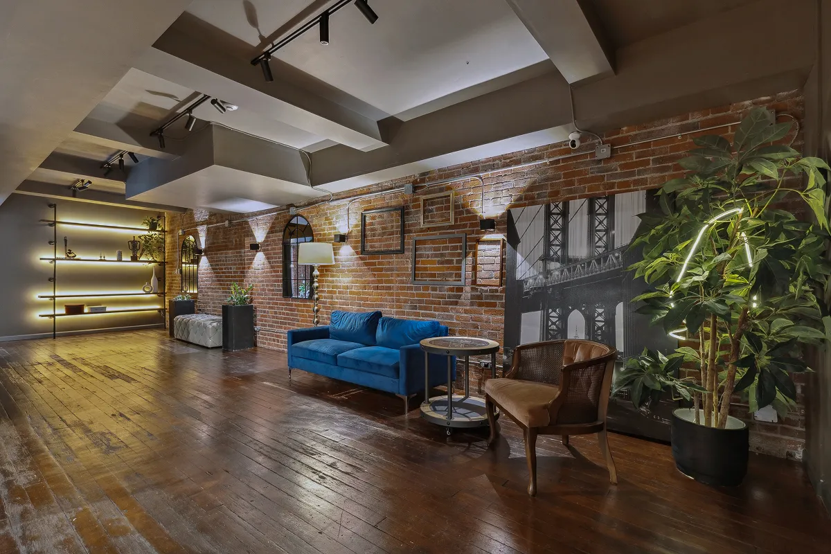 Open loft event space with green sofa, projector screen and exposed brick wall at Click Click Gastown