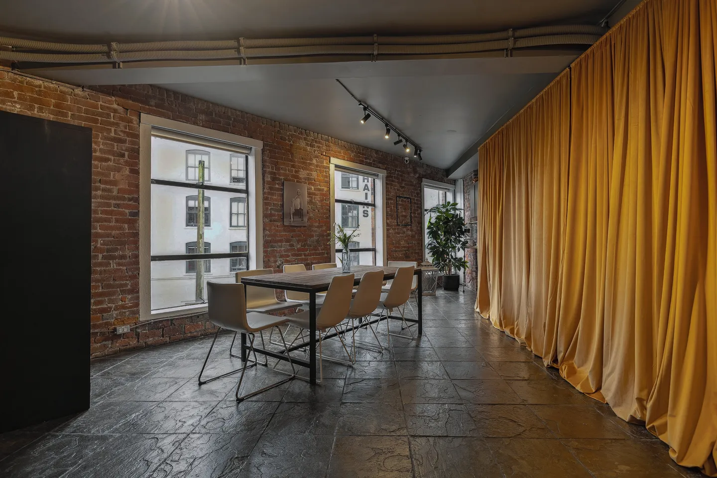 Dining area with yellow curtain and long table at Click Click loft event venue in Gastown, Vancouver