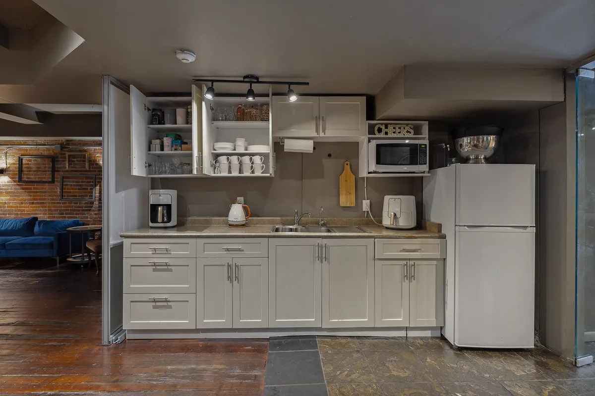 Fully equipped kitchen with white cabinets and tableware at Click Click event venue in Vancouver