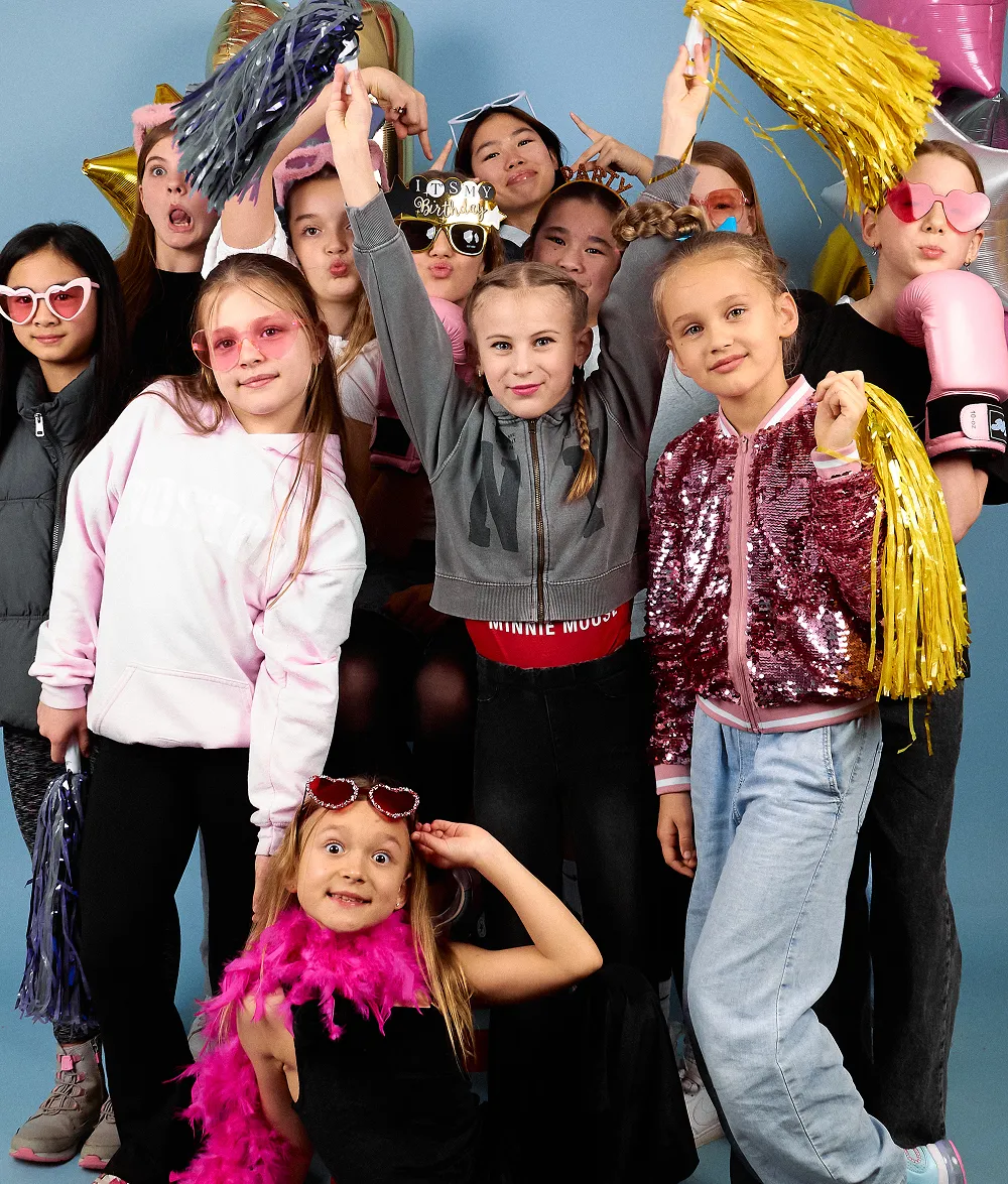 Children posing with a giant teddy bear and costume props at a birthday party
