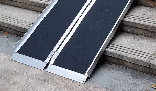 Two portable black ramps with silver edges placed on concrete stairs for wheelchair access.