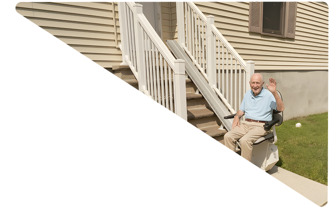 Elderly man smiling and waving while seated on a stair lift outside a house with beige siding.