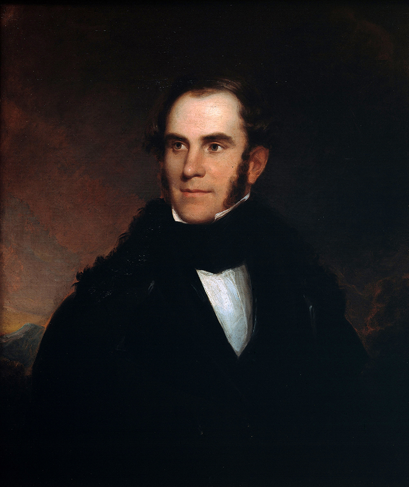 Portrait of a man with sideburns wearing a black coat and white shirt against a dark background.