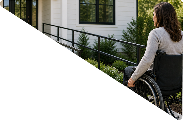 Elderly man smiling and waving while seated on a stair lift outside a house with beige siding.