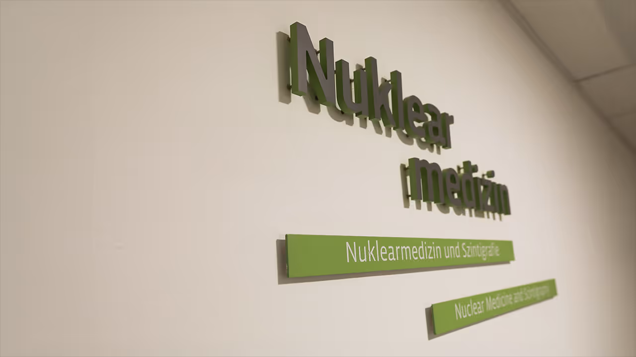 Green 3D letters on a white wall display “Nuclear Medicine” and similar terms, indicating a nuclear medicine department.