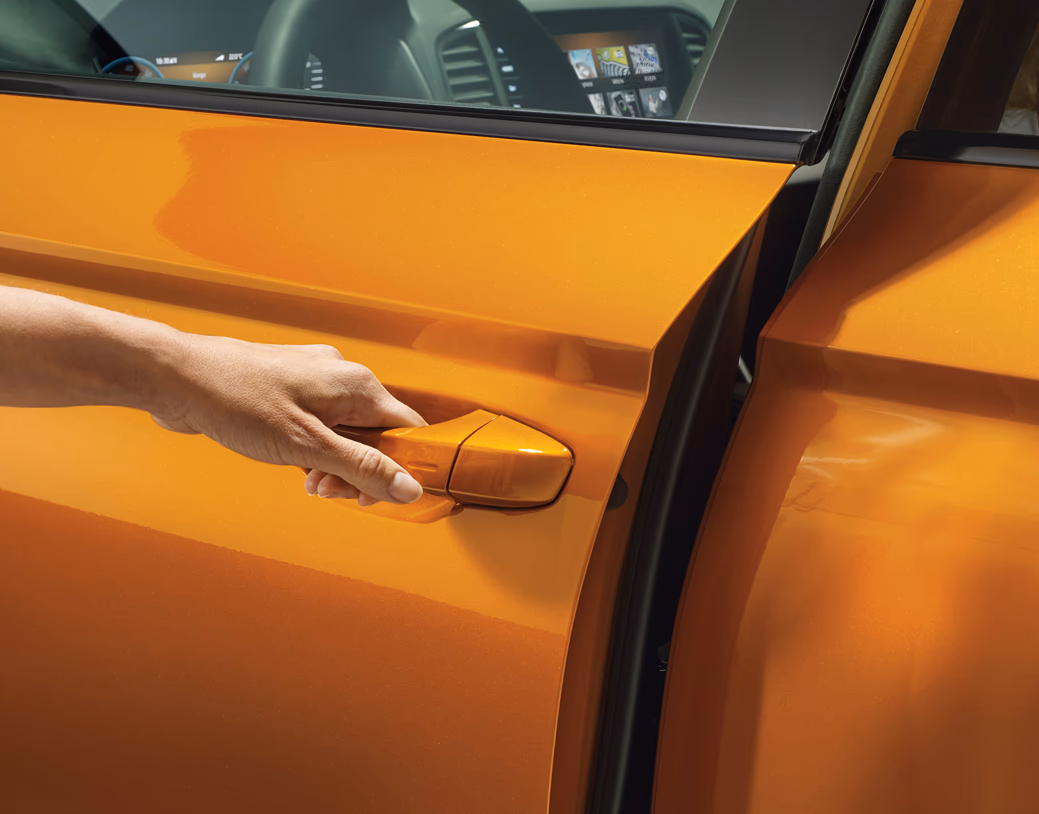 Eine Nahaufnahme zeigt die Hand einer Frau beim Öffnen der Tür eines Škoda Karoq Balance in der Lackierung Phoenix-Orange Metallic.