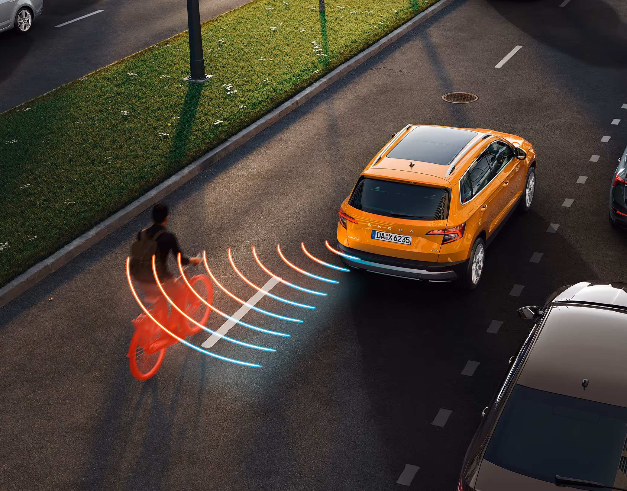 Animation des Spurwechselassistenten: Aus dem toten Winkel nähert sich von der linken Seite ein Fahrradfahrer dem orangefarbenen Škoda Karoq Balance. Das System warnt vor der möglichen Gefahrensituation.