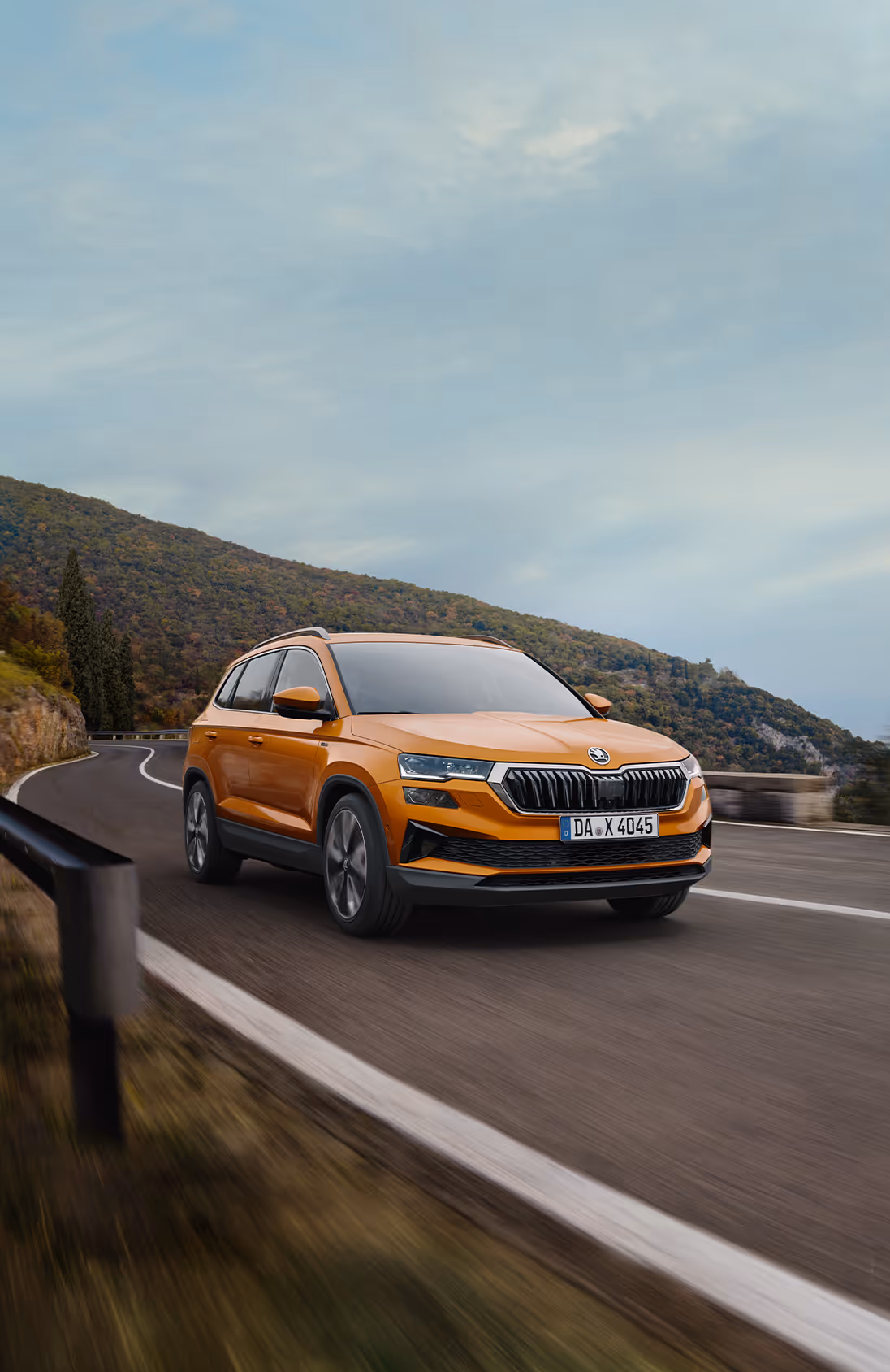 Eine Nahaufnahme der Frontpartie des Škoda Enyaq in der Farbe Olibo-Grün Metallic. Im Fokus steht der beleuchtete, markante Kühlergrill, der zusammen mit den Voll-LED-Matrix-Scheinwerfern das moderne und selbstbewusste Design unterstreicht. Unten rechts steht auf einer dunkelgrün abgesetzten Fläche der Schriftzug „Sicherheit und Assistenten“.