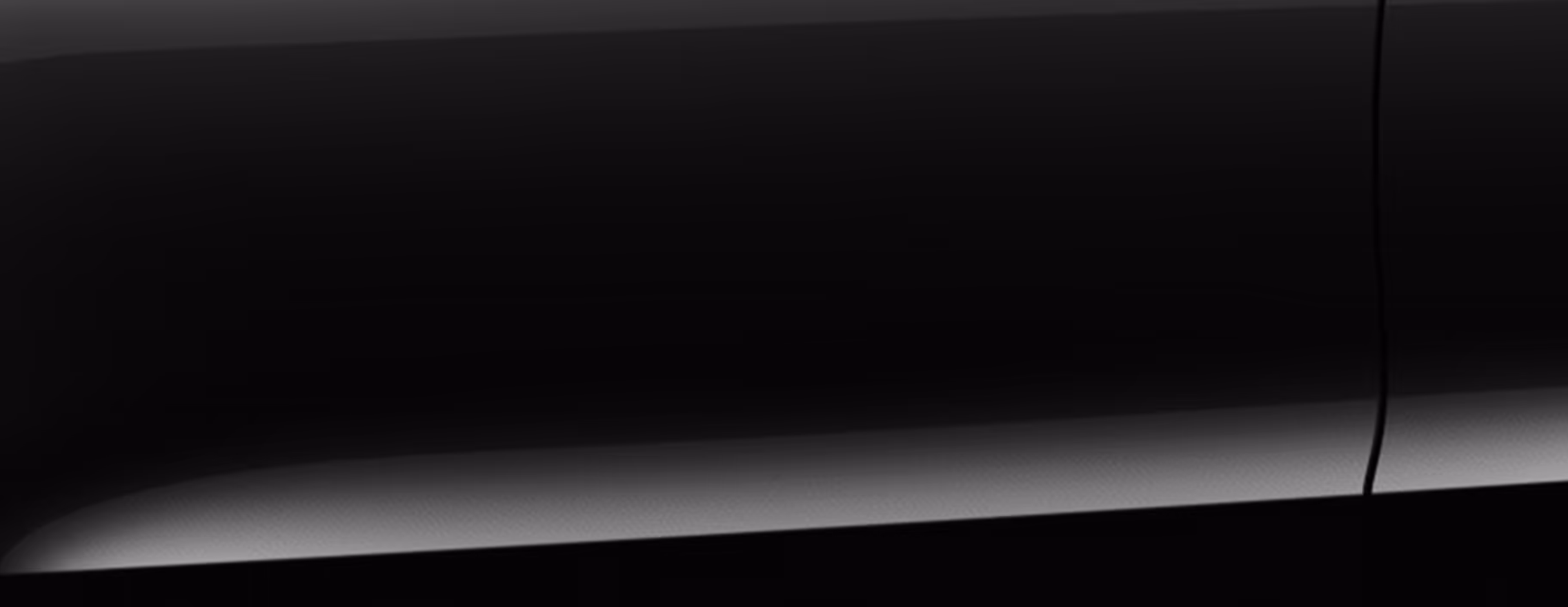 Eine minimalistische Detailaufnahme zeigt einen Ausschnitt der Karosserie des Škoda Karoq Balance in der Lackierung Black-Magic Perleffekt. 
