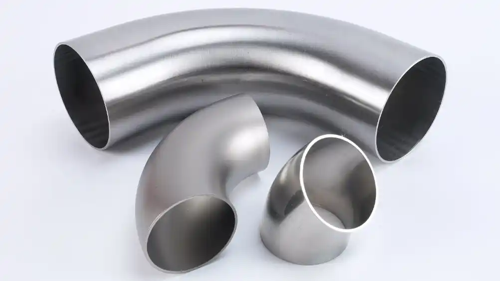 Tre bøygede rustfrie stålrør i forskjellige størrelser på hvit bakgrunn.