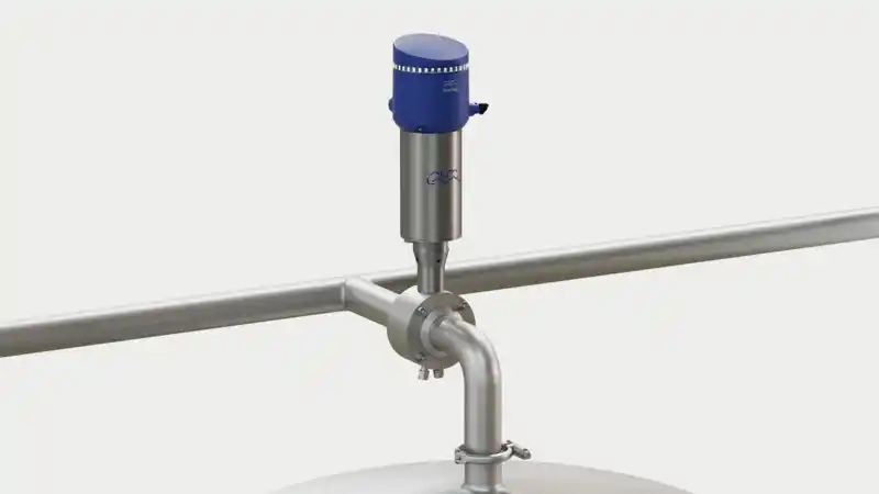 En industriventil med en blå aktuator montert på et rørsystem over en tank.